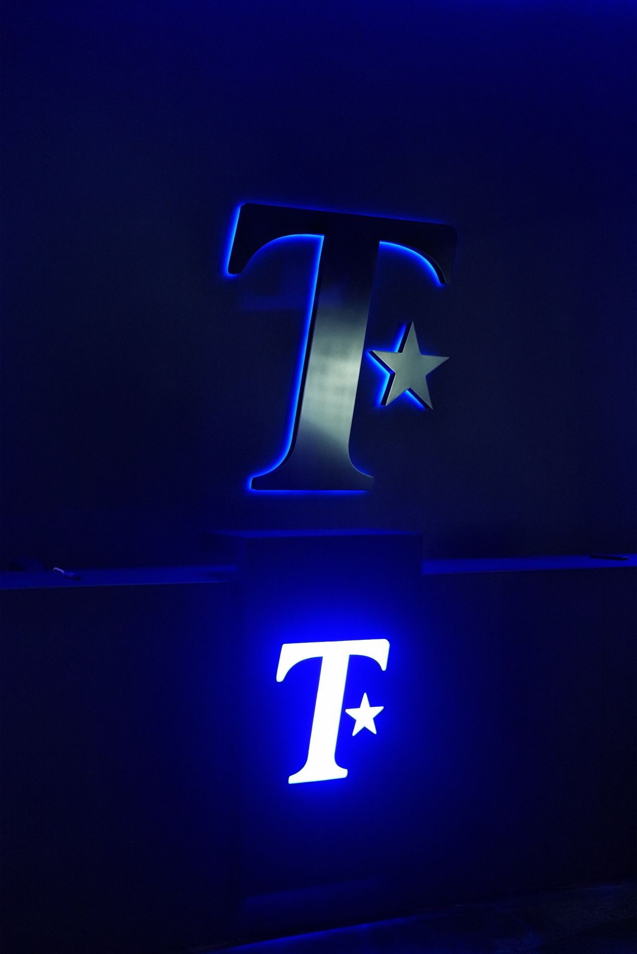 Logo T lumineux au mur du salon Treatment Charleroi
